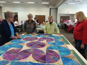 Four quilters study a work in progress